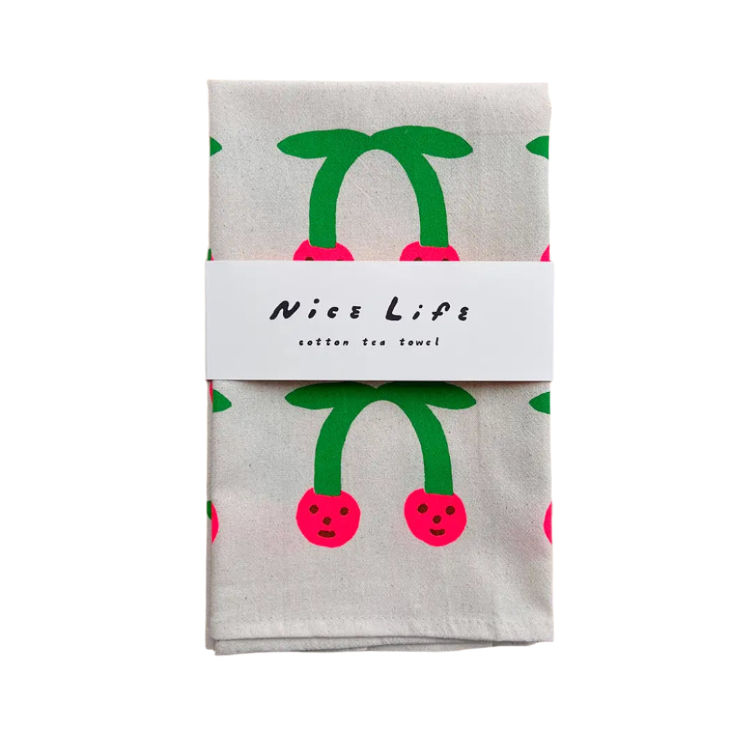 Packaged cotton tea towel with cherry design on a wooden surface