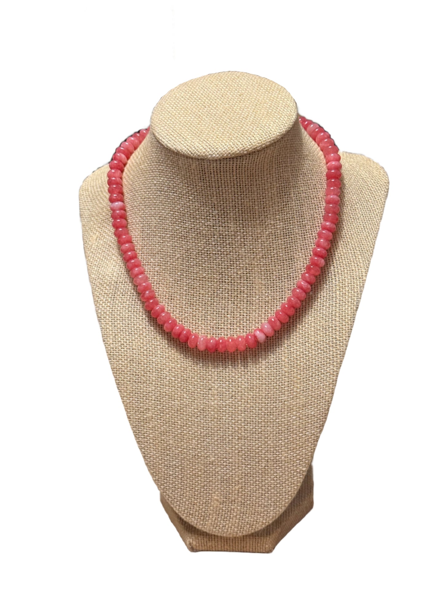Pink beaded bracelet on a beige jewelry display stand.