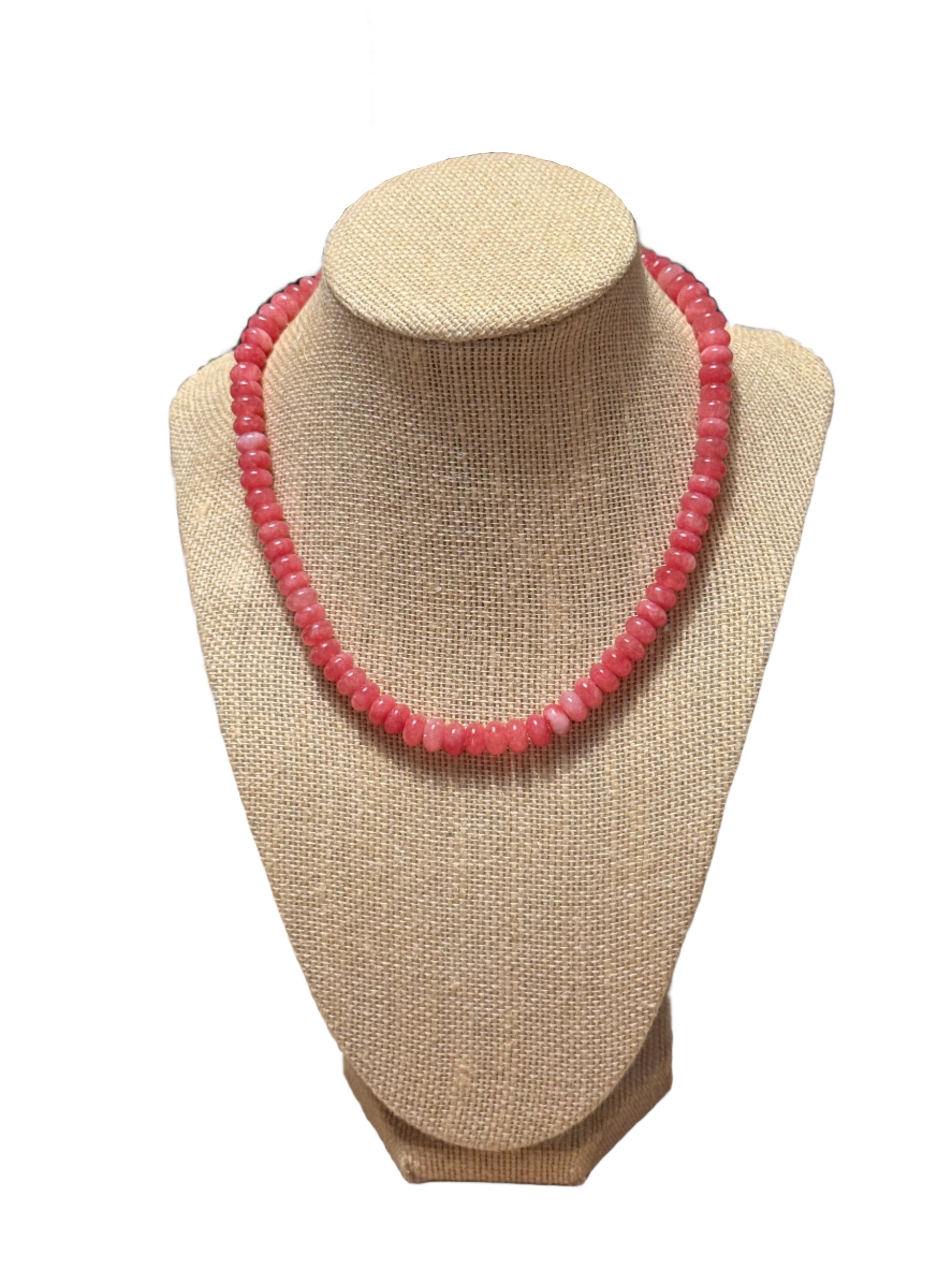 Pink beaded bracelet on a beige jewelry display stand.