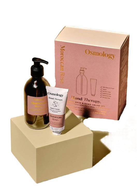 Osmology Moroccan Rose hand therapy set with bottle, cream, and packaging on a beige background