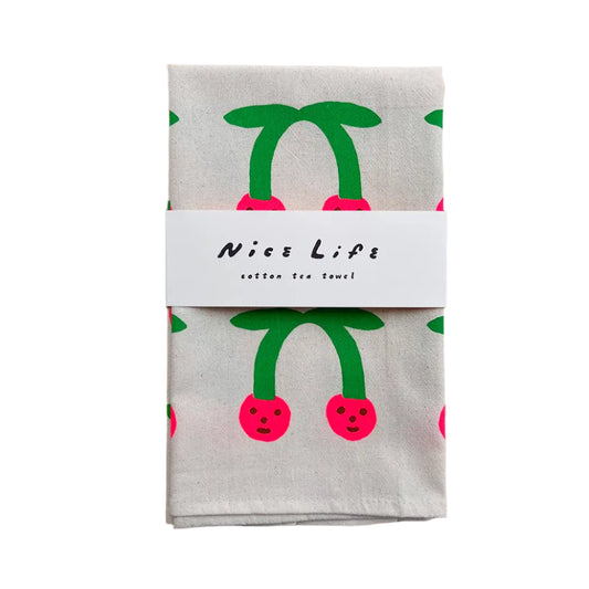 Packaged cotton tea towel with cherry design on a wooden surface